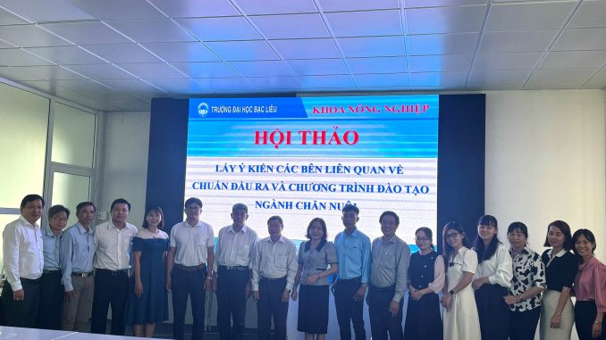 A group of people standing in front of a large screenDescription automatically generated